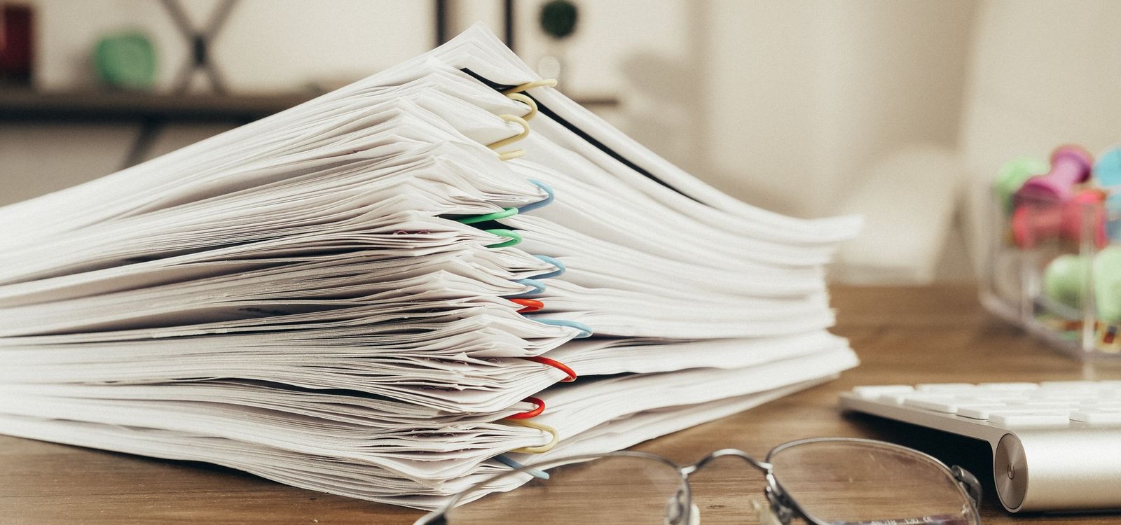 Notaires, bailleurs, syndics et services sociaux Pile de documents classés sur un bureau, symbole du suivi administratif d'un dossier